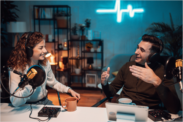 Two podcasters sitting down and talking to each other.